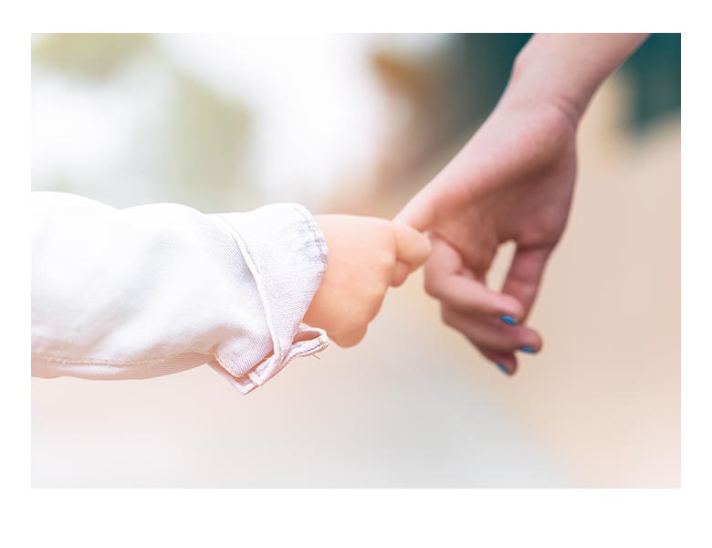 Close-up of baby's hand holding parent's hand, symbolizing the supportive and nurturing care of Play at Home Physical Therapy